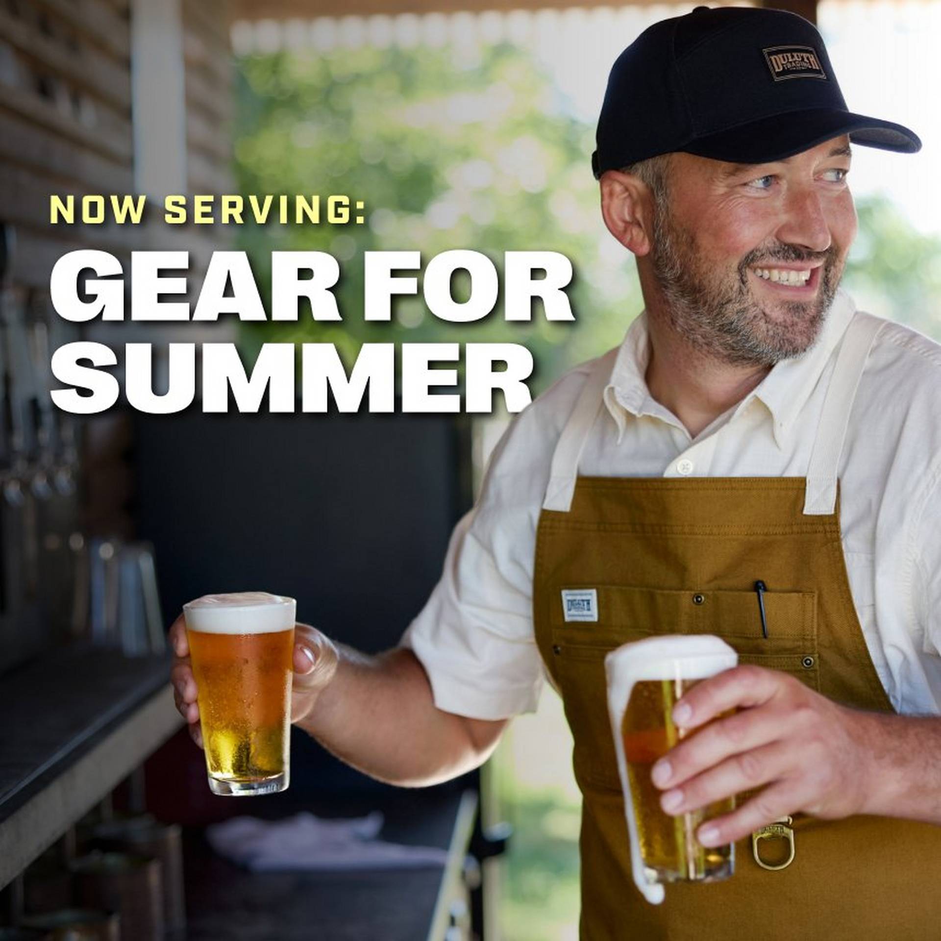 Man wearing black ball cap and tan apron, holding two beers.