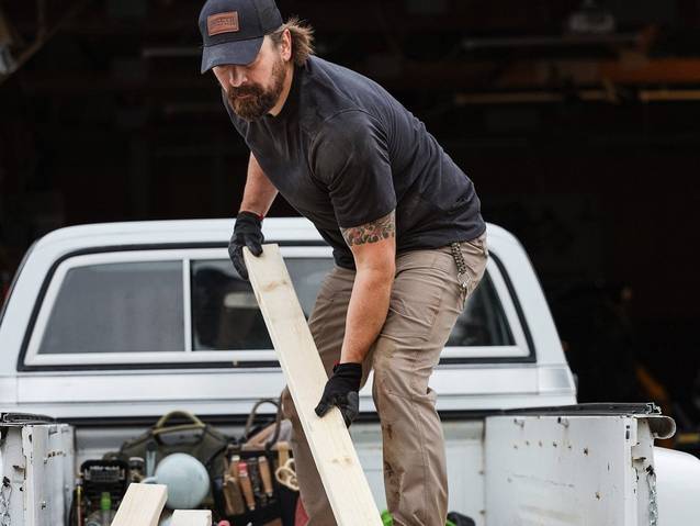 Man loading lumber into back of pickup truck.