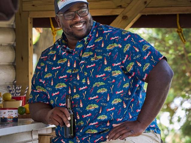 Man holding a beer bottle, smiling.