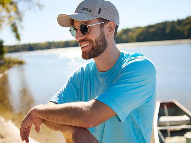 Man wearing blue t-shirt, grey hat and sunglasses.