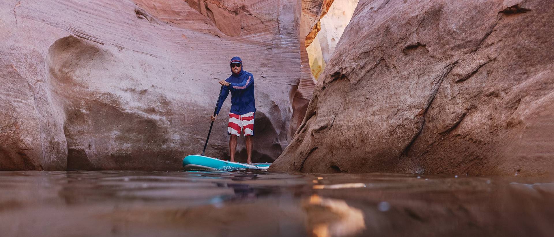 Man paddleboarding through canyon.