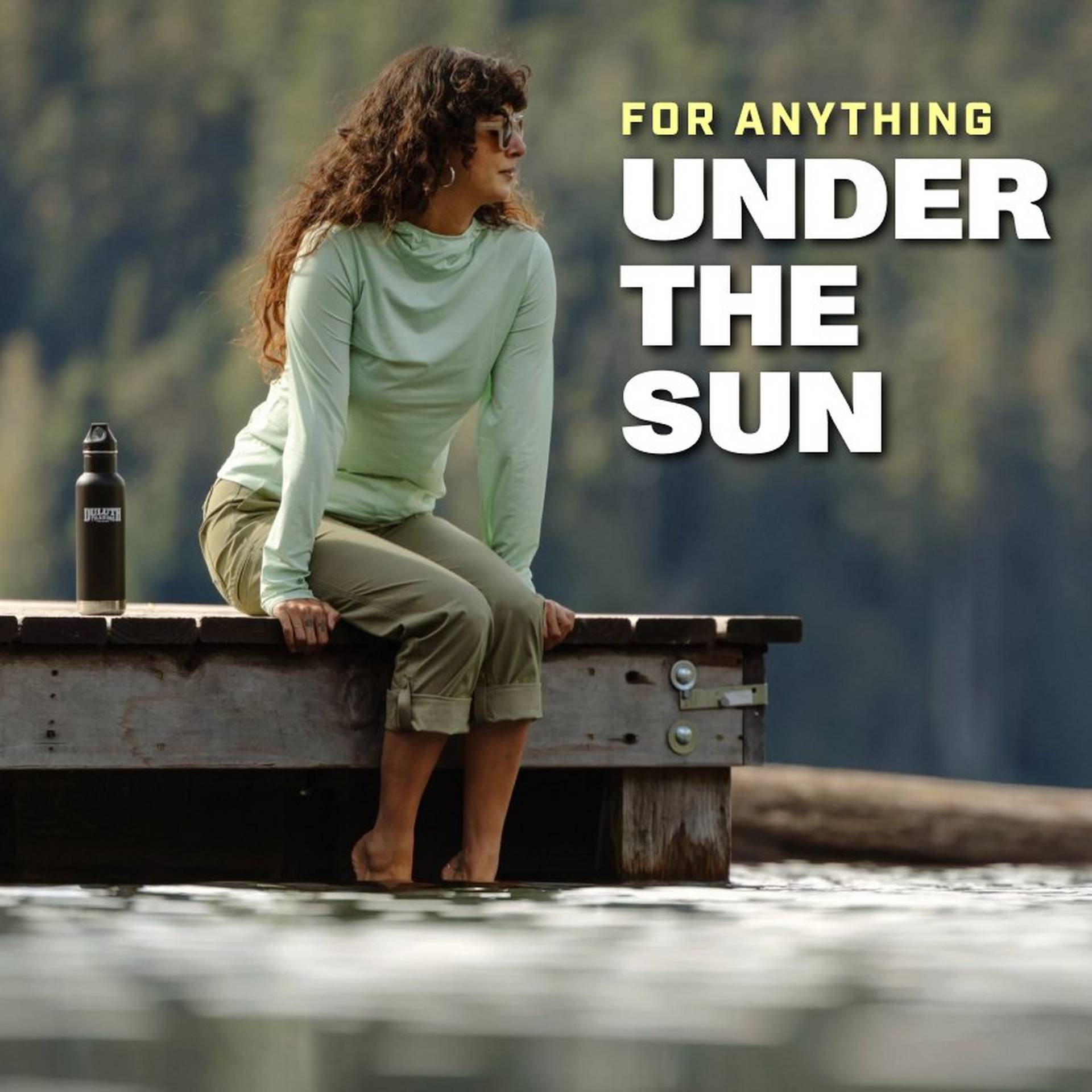 Woman wearing a mint green long sleeve and capri pants, sitting on dock.
