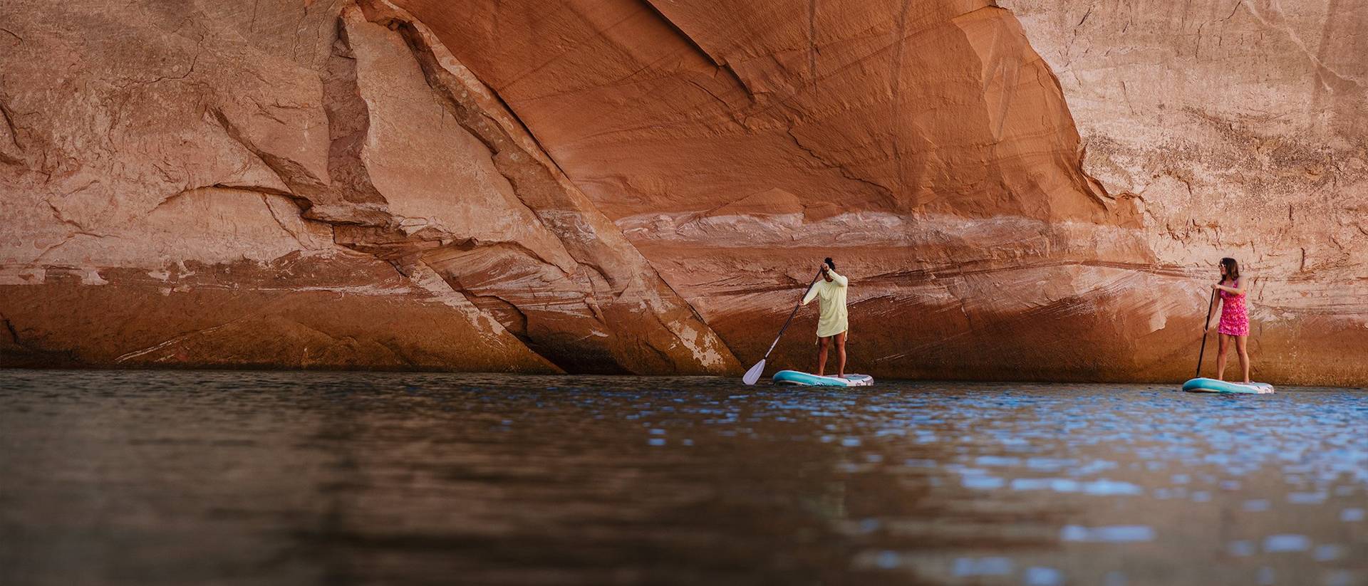 Two women paddleboarding in canyon.