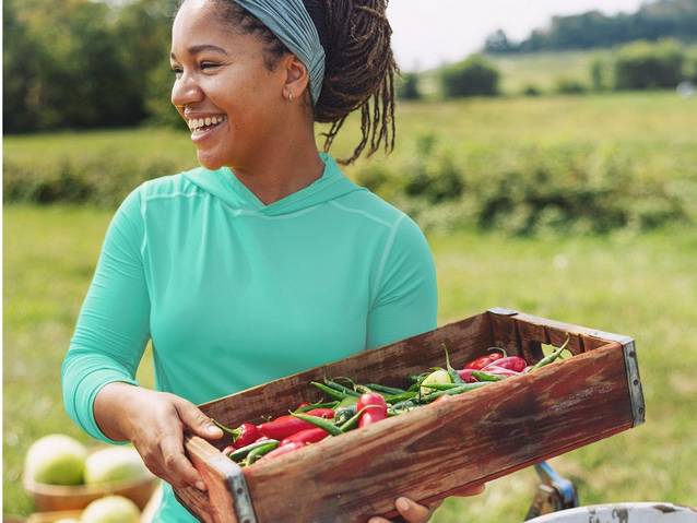 Woman holding tray of peppers and beans.