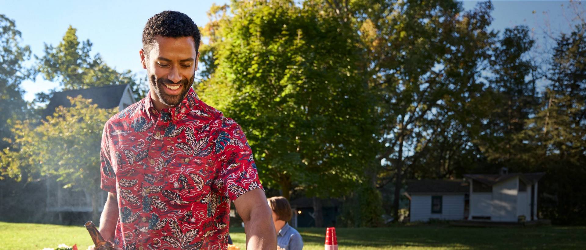 Man in red shirt, grilling.