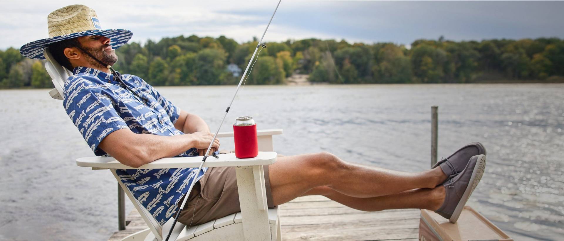 Man in blue shirt sitting in chair on a dock.