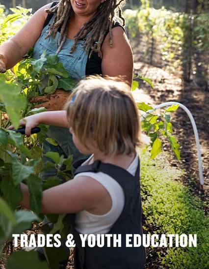 child trimming plants in overalls next to a woman