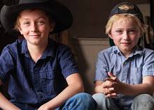 two boys with hats and blue shirts sitting next to each other