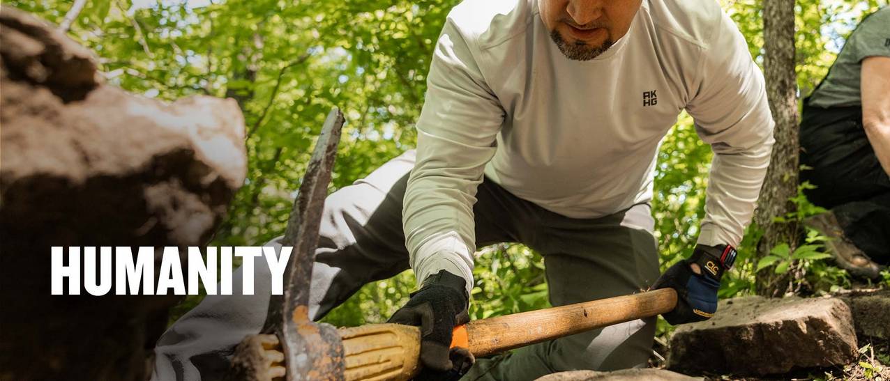 man wearing a white shirt and grey pants with a pickaxe