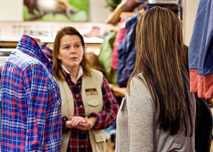 Woman in a grey shirt shares information to woman in a red flannel and tan vest