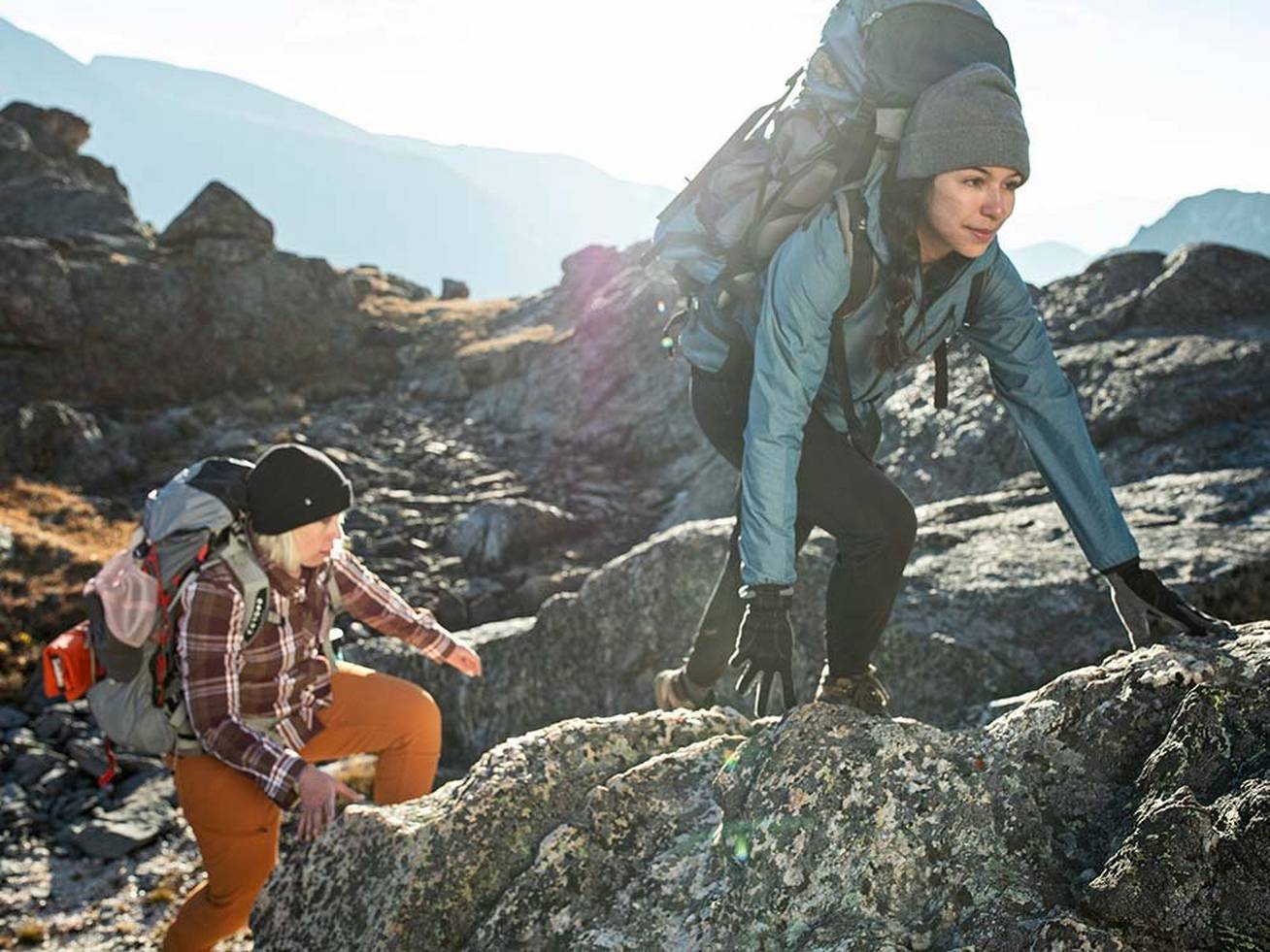Women climbing rocks with hiking gear