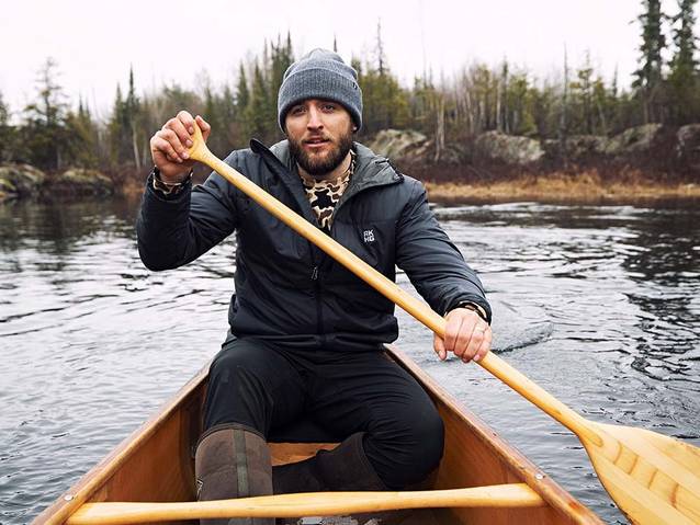 Man in a canoe wearing a gray hat and a black AKHG jacket