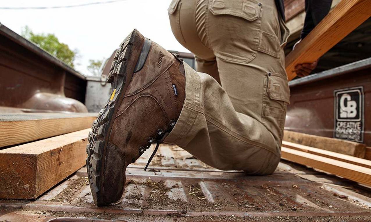 man kneeling in bed of truck with brown boots on