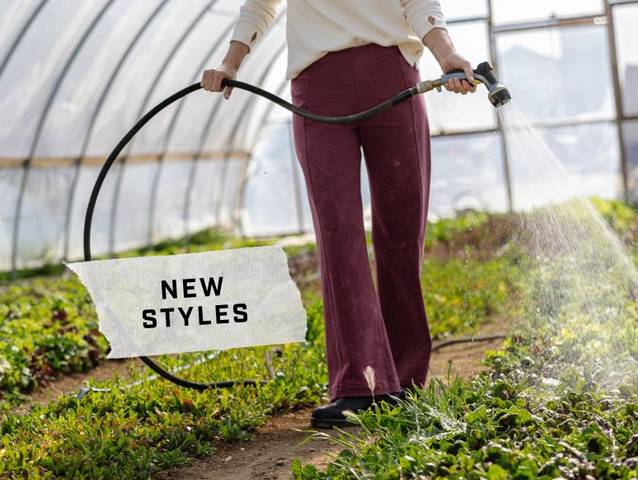 Woman wearing purple stretchy pants, watering plants in greenhouse.