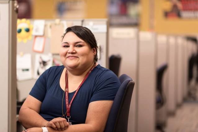 Smiling woman sitting in cubicle.