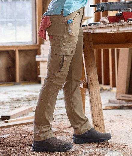 A woman in khaki cargo pants cuts with a band saw