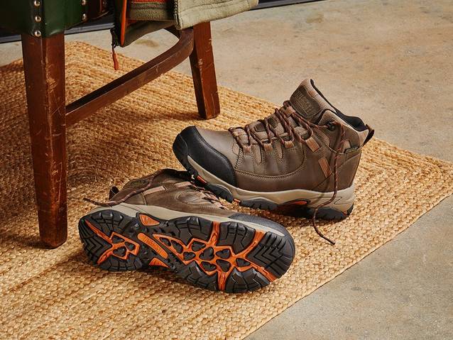 A pair of boots sit on a jute rug