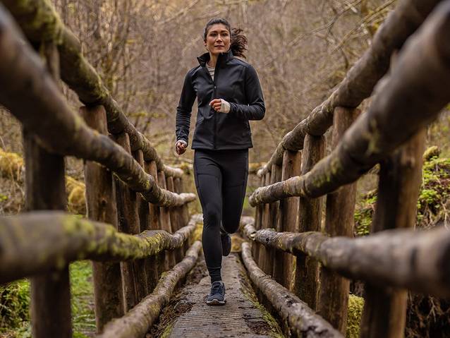 A woman runs on a wooden bridge in the woods