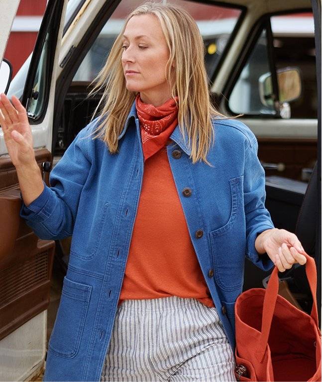 Woman wearing an orange turtleneck and blue jacket.
