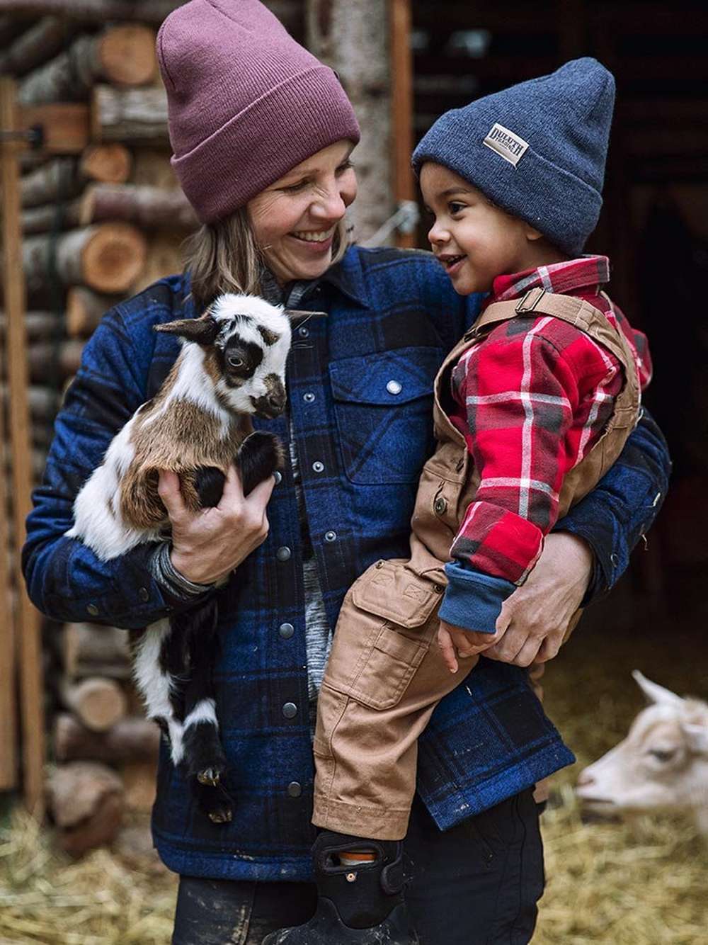 woman and child wearing flannel shirts and carrying a baby goat