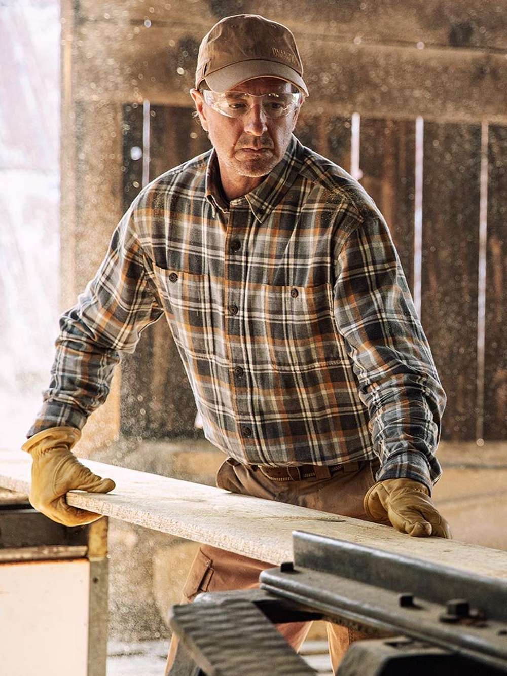 man working in a saw mill wearing flannel shirt