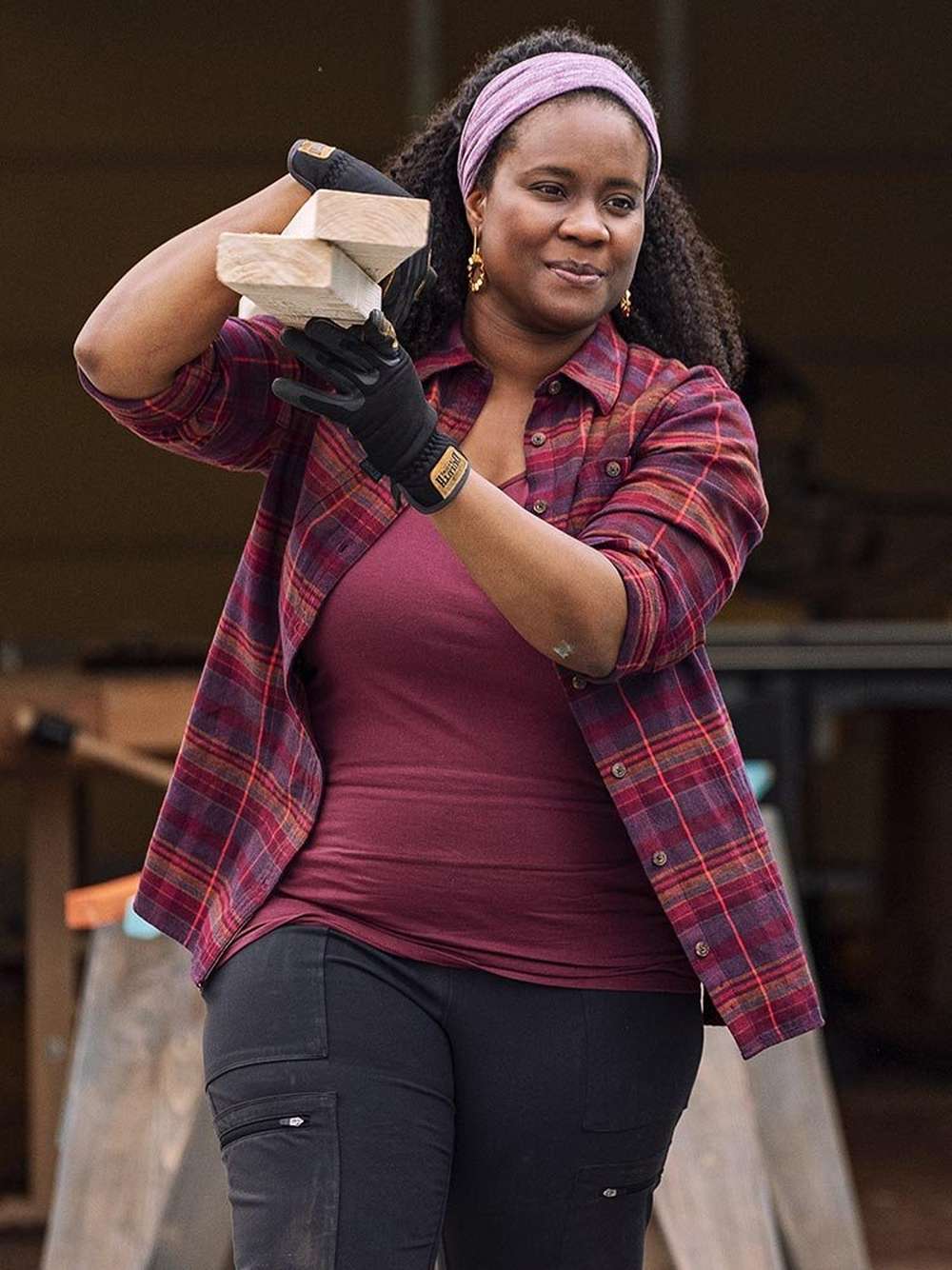 woman carrying lumber wearing flannel shirt