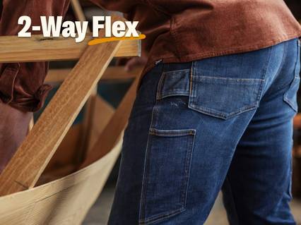 Headline: 2-Way Flex. Man wearing jeans while working.