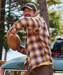 Man wearing flannel throwing a football.