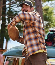 Man wearing flannel throwing football.