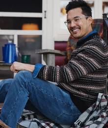 Man wearing striped sweater, smiling.