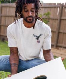 Man wearing white tee with eagle on it.