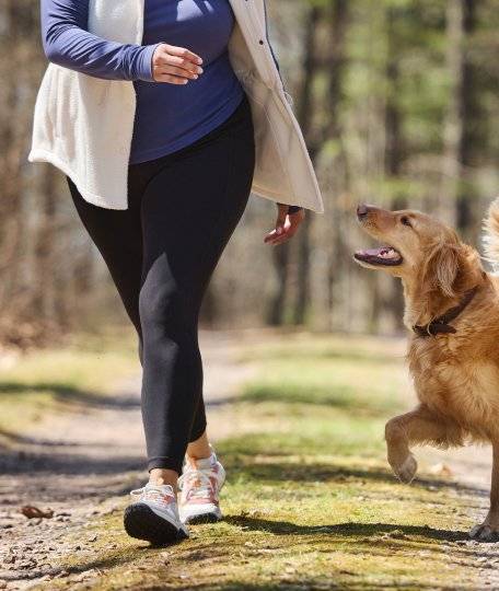 Woman wearing leggings, running next to dog.