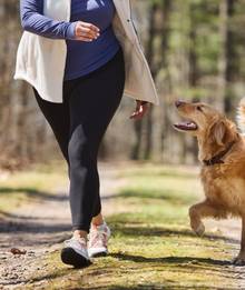 Woman wearing leggings, running next to dog.