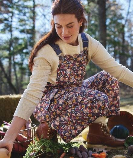 Woman crouching in purple patterned overalls.