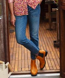 Woman standing in door way wearing jeans.