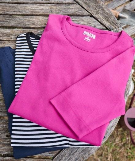 Women's shirts folded and stacked on table.
