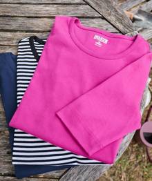 Women's shirts folded and stacked on table.