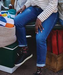 Woman sitting on tailgate wearing jeans.