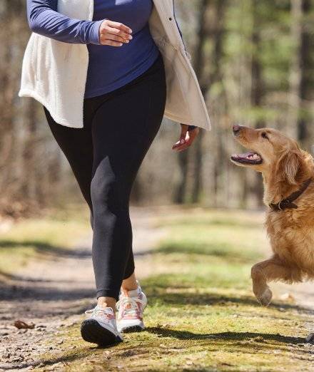 Woman wearing leggings, jogging next to dog.
