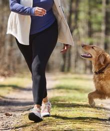 Woman wearing leggings, jogging next to dog.