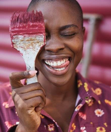 Woman with paintbrush near her face.