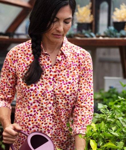 Woman in floral top watering plants.