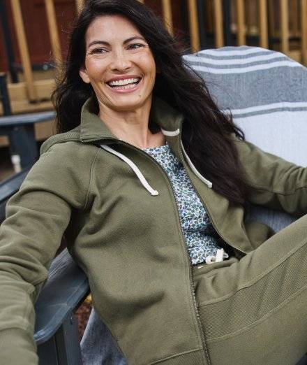 Woman wearing green zip-up hoodie, smiling.
