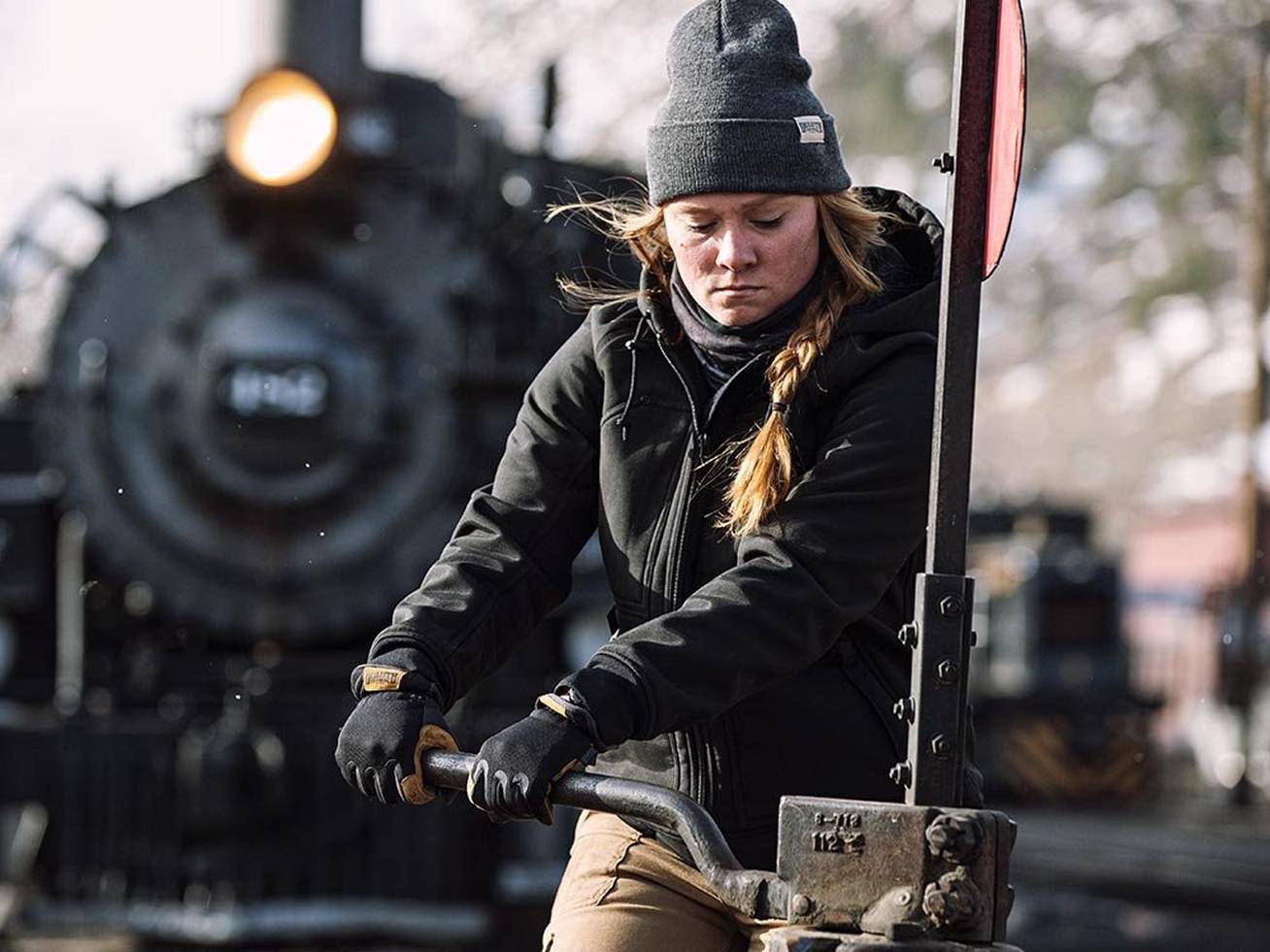 Woman in black coat works in a train yard