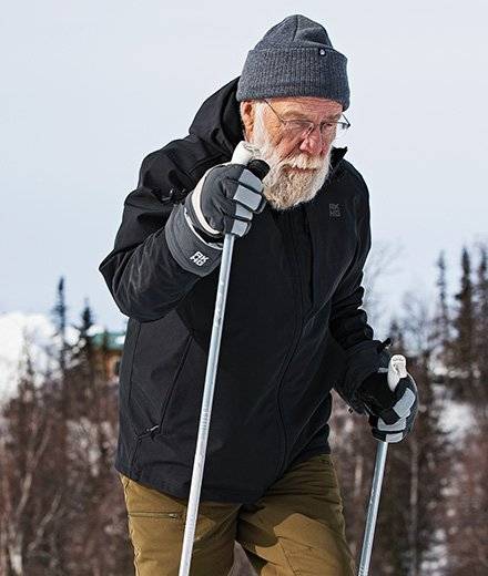 A man in a black coat cross-country skiing