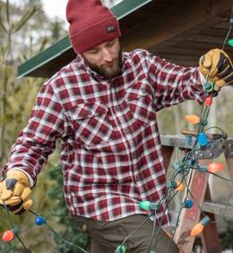 Man on ladder hanging string lights