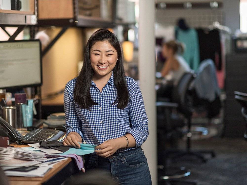 a smiling woman stands in an office