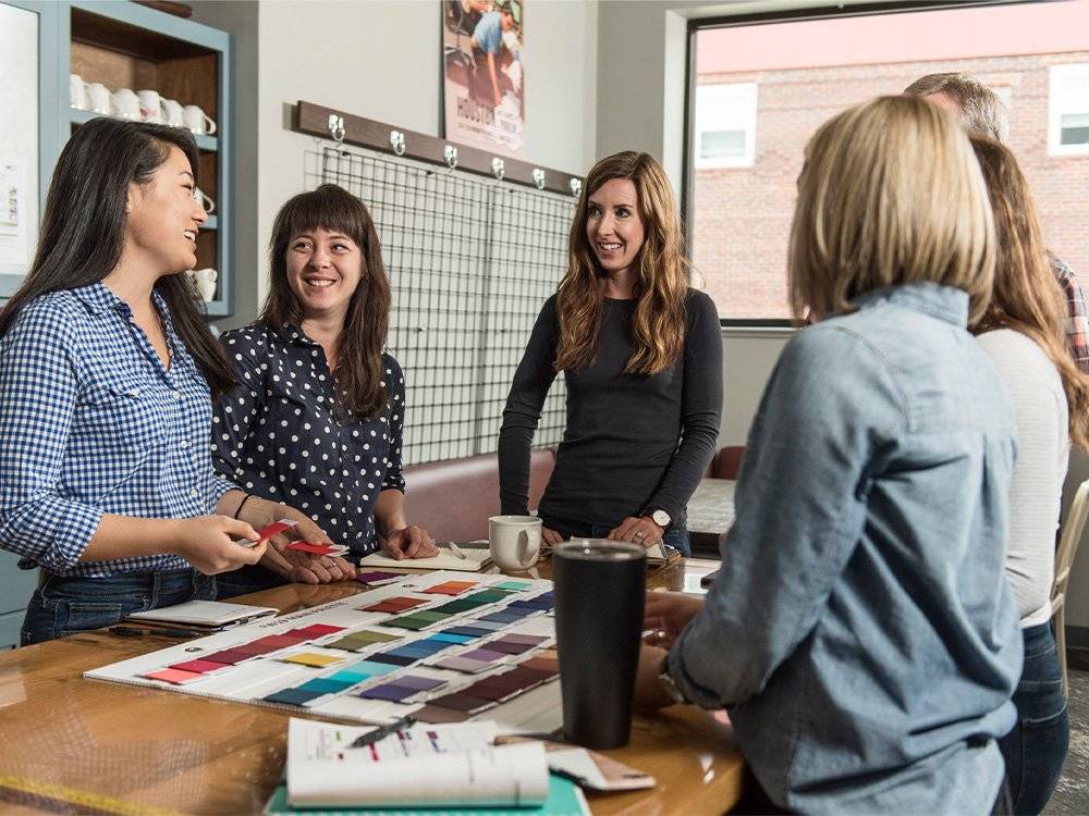 a group of coworkers discuss fabric swatches in an office
