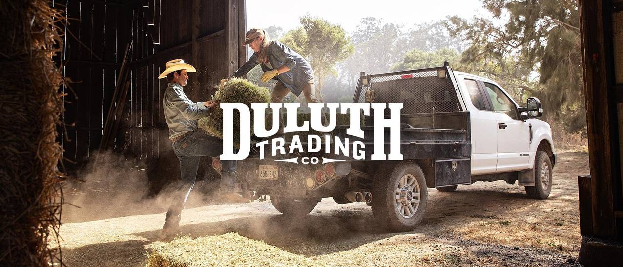 man and woman loading hay bale into truck