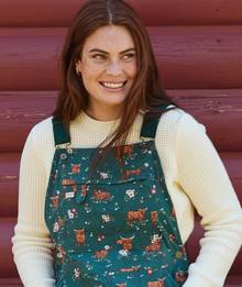 Woman wearing cow printed overalls.